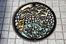 篠山城跡の石垣と町の花「ささゆり」町の木「マツ」が描かれた篠山町のマンホールです。